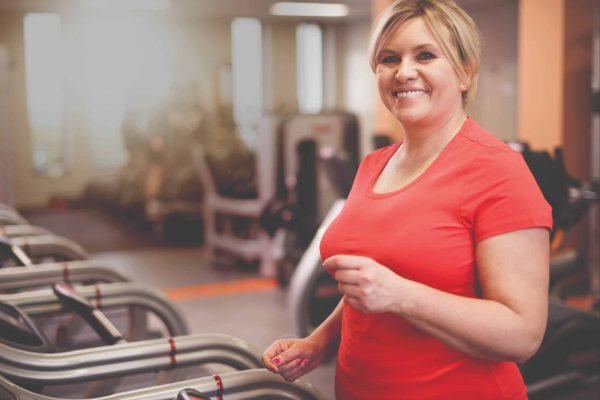 Woman in red shirt on treadmill smiling